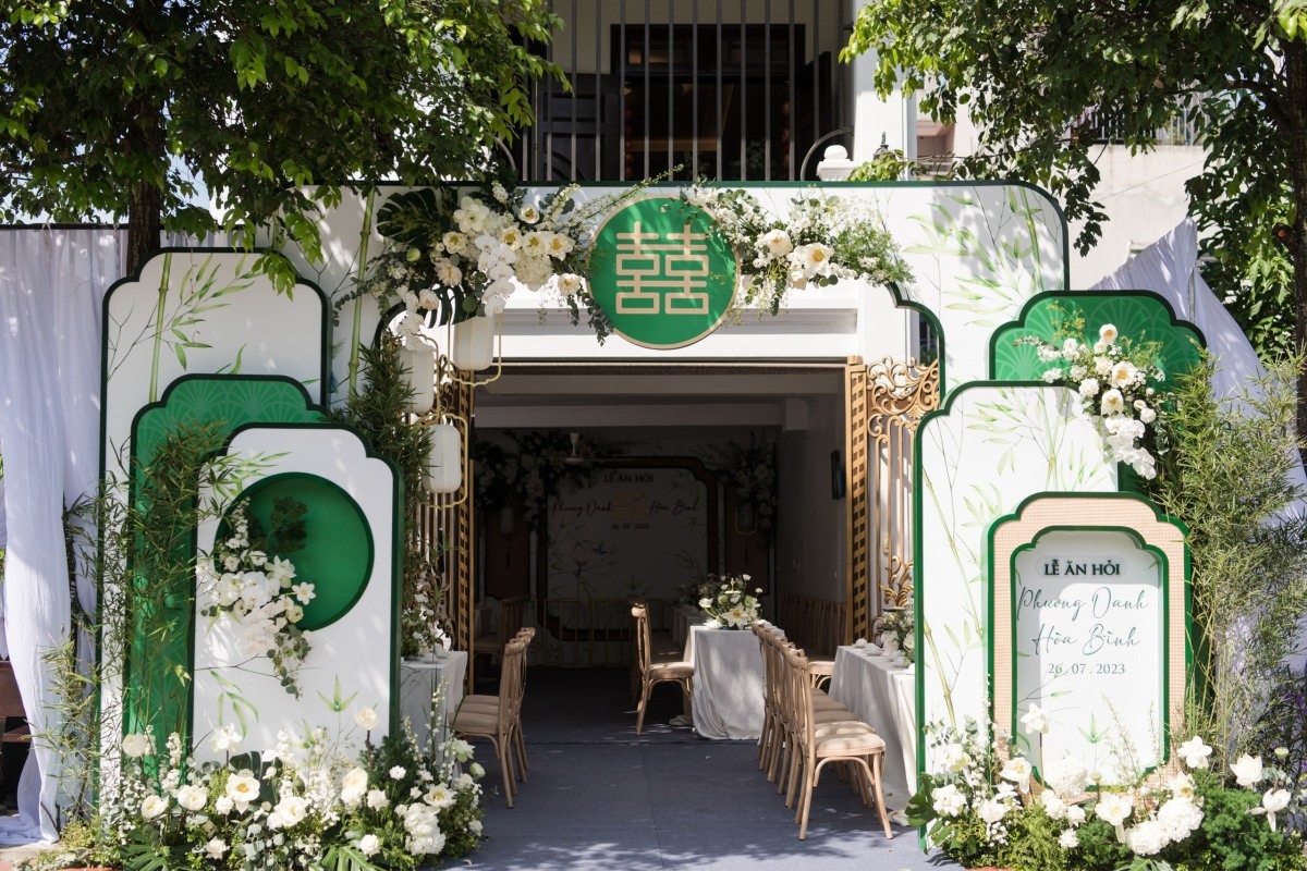 Cổng cưới được trang trí toàn bằng hoa tươi, được dựng phía trước cửa chính của căn nhà màu trắng