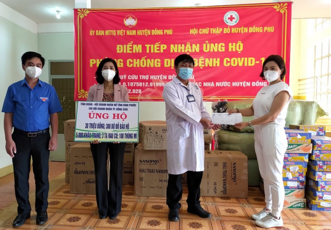 Chị Nguyễn Thị Ngọc Minh, Chi hội trưởng Chi hội Nữ doanh nhân TP Đồng Xoài (bìa phải) cùng Bí thư Tỉnh Đoàn Trần Quốc Duy (bìa trái) trao các nguồn hỗ trợ cho huyện Đồng Phú