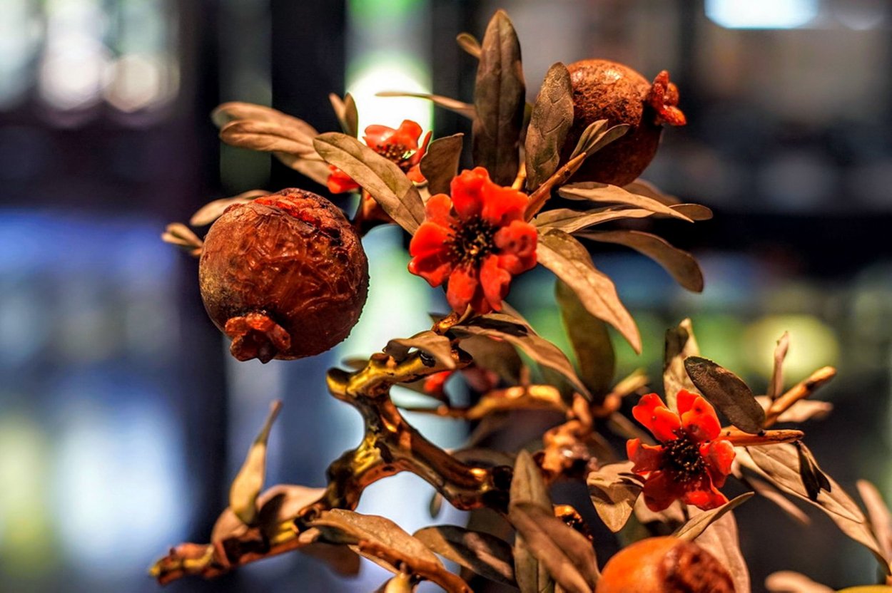Cây có thân bằng gỗ thếp vàng. Cánh hoa và quả màu đỏ cam, lá màu xanh nhạt, đều được làm bằng đá tự nhiên.