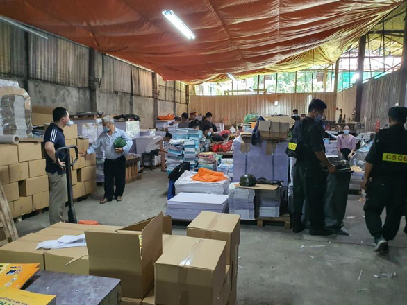Cơ quan chức năng kiểm tra một cơ sở sản xuất sách giả - Ảnh: GIANG LONG