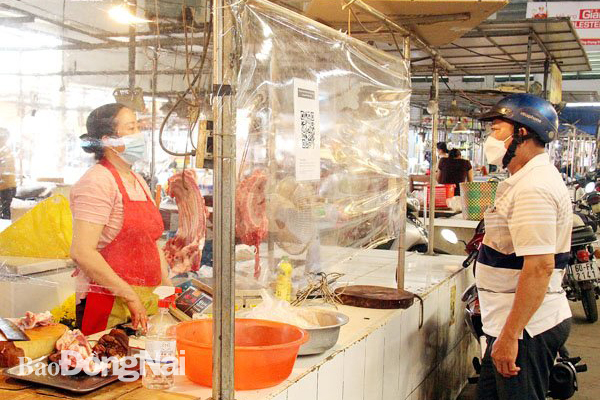 Một sạp bán thịt heo ở chợ Tân Hiệp (TP.Biên Hòa) bố trí mã QR của sạp để người mua khai báo y tế và triển khai vách ngăn nhằm đảm bảo phòng, chống dịch, vệ sinh an toàn thực phẩm. Ảnh: H.Quân