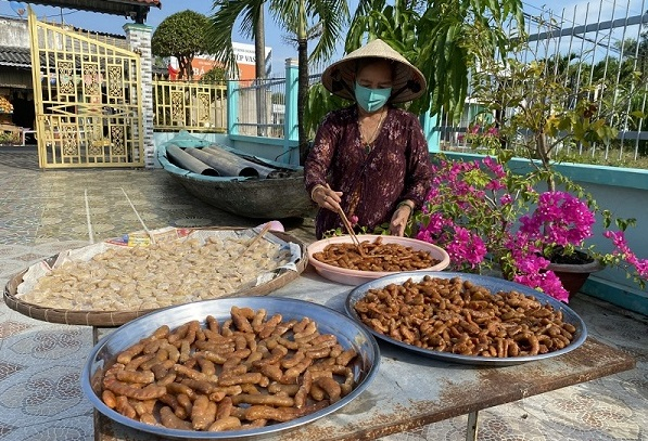 Bà Trương Thị The (75 tuổi, ngụ ấp 4, xã Tân Thành) tất bật bên khay mứt để kịp giao cho khách (Ảnh: Cổng TTĐT Cà Mau).