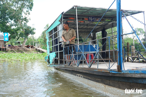 Ông Phan Văn Xuyến cho đàn cá tra tự nhiên ăn - Ảnh: HOÀI THƯƠNG
