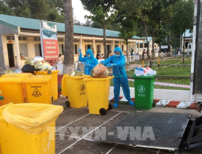 Các nhân viên Công ty Cổ phần Nước – Môi trường Bình Dương (Biwase) thu gom rác thải y tế ở các khu điều trị bệnh nhân COVID-19. Ảnh: Huyền Trang -TTXVN