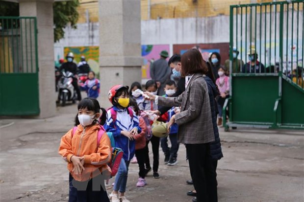 Đo thân nhiệt và nhắc nhở các em học sinh đeo khẩu trang khi vào trường. (Ảnh minh họa: Trọng Đạt/TTXVN)