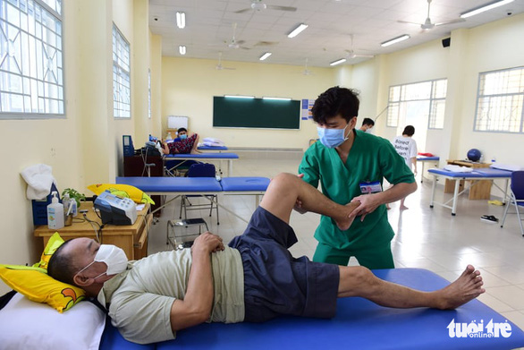 Nhân viên y tế Bệnh viện Lê Văn Thịnh hướng dẫn các bài tập vật lý trị liệu cho bệnh nhân để họ nhanh chóng phục hồi sức khỏe hậu COVID-19 - Ảnh: DUYÊN PHAN