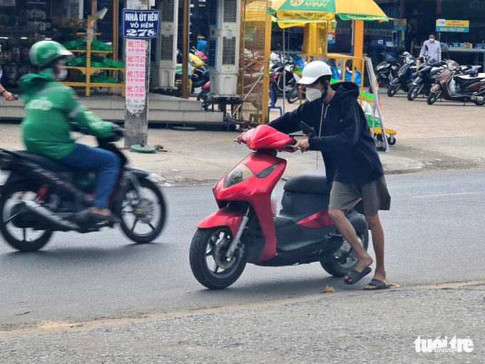 Nhiều người dân có xe hết xăng nên phải dắt bộ đi ngang qua cây xăng trên đường Phạm Văn Chiêu (quận Gò Vấp) vào trưa 20-2. Đứng trong cây xăng nhìn thấy cảnh này, nữ nhân viên cây xăng nói rằng 