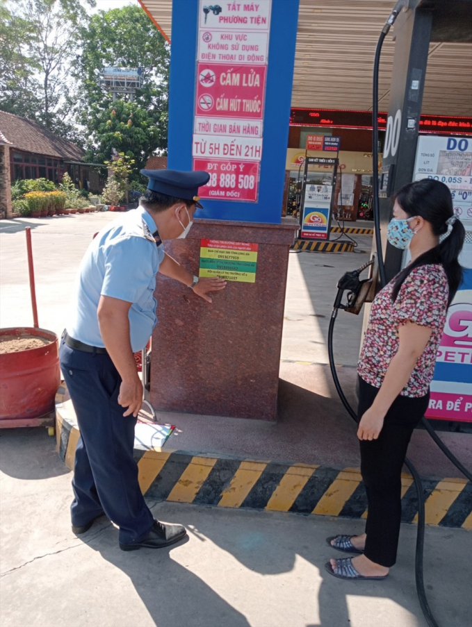 QLTT hướng dẫn người dân thông tin tiếp nhận phản ánh về kinh doanh xăng dầu được công bố tại các cây xăng trên toàn tỉnh. Ảnh: An Long