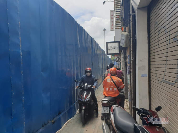 rong ảnh, người dân luồn lách di chuyển qua 'con hẻm' dọc tuyến đường Lê Lợi khi hàng rào tôn được dựng