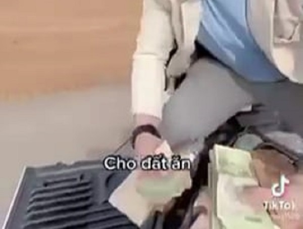Nam thanh niên cầm từng cọc tiền ném xuống “cho đất ăn” (ảnh cắt từ clip)