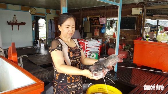Bà Nguyễn Thị Hòa cầm con cá lăng đuôi đỏ hơn 3kg vừa bị chết sáng 14-5 - Ảnh: BỬU ĐẤU