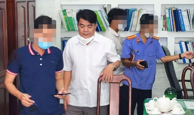 Ông Lành (áo trắng) tại thời điểm cơ quan chức năng khám xét nơi làm việc. Ảnh: E.X
