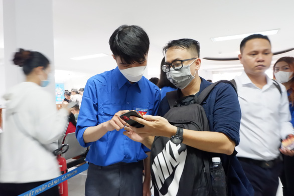 Thanh niên tình nguyện (trái) hướng dẫn người dân đến cấp, đổi hộ chiếu tại Phòng quản lý xuất nhập cảnh Công an TP.HCM - Ảnh: K.ANH