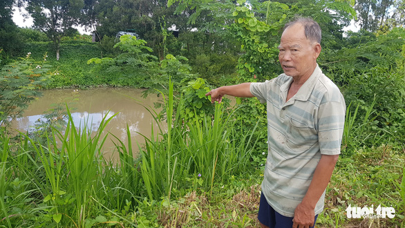 Ông Năm To chỉ tay xuống kênh 7, thuộc xã Mỹ Phú, huyện Châu Phú - nơi có đường ống nước thải của vùng nuôi cá tra Lộc Kim Chi đâm thẳng xuống - Ảnh: BỬU ĐẤU