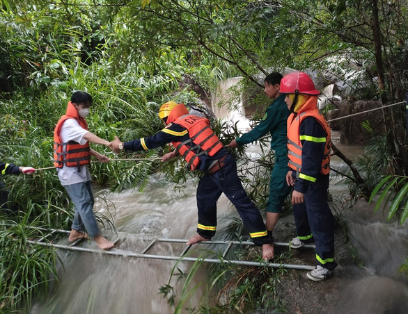 Đội cứu hộ dùng thang giải cứu người mắc kẹt ở khu vực suối Tiên do mưa lớn, nước chảy cuồn cuộn - Ảnh: Công an cung cấp