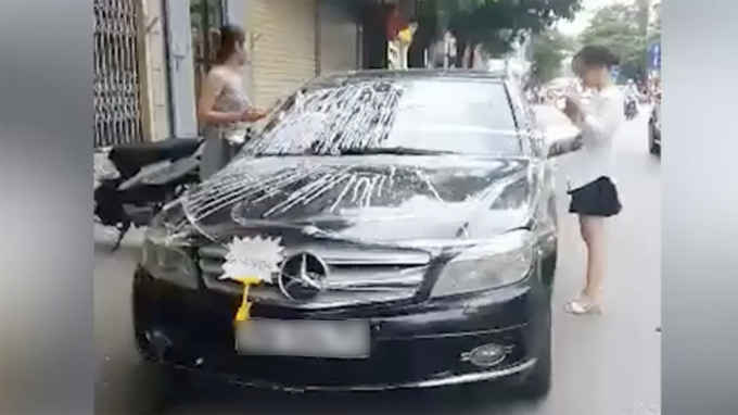 Hình ảnh 2 cô gái đang dán băng dính quanh chiếc Mercedes CHỤP MÀN HÌNH