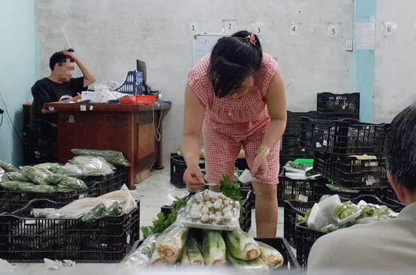 Công nhân dán tem VietGAP vào gói rau mua từ chợ đầu mối đã được sơ chế - Ảnh: BÔNG MAI