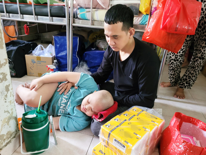 Để có tiền lo thuốc men cho con, anh Nguyễn Thanh Phong Em tranh thủ lấy khăn giấy đi bán trong bệnh viện