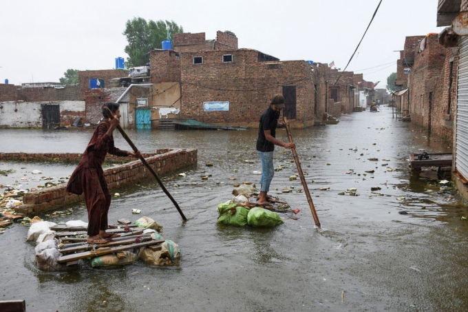 Người dân ở Pakistan phải dùng những chiếc bè tạm để di chuyển trên các tuyến đường ngập do mưa lũ. Bộ trưởng Khí hậu Pakistan hồi tháng 8/2022 cho biết 1/3 diện tích đất nước bị ngập. Ảnh: Reuters.