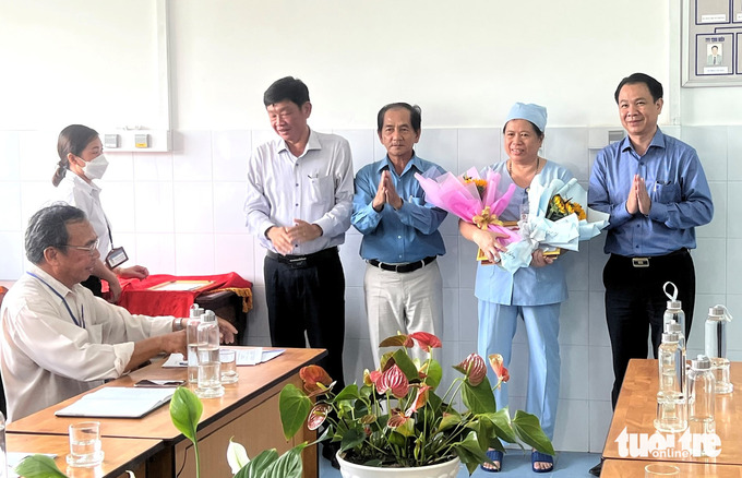 Ông Trần Quang Hiền, giám đốc Sở Y tế tỉnh An Giang (bìa phải), tặng hoa và khen thưởng cho chị Uông Mỹ Hạnh - Ảnh: Sở Y tế cung cấp