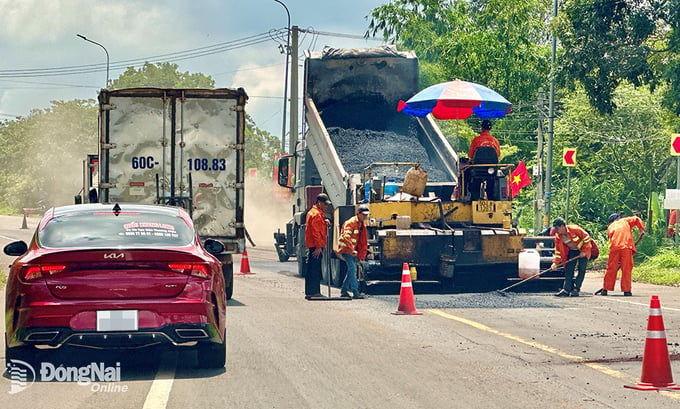 Công nhân thảm nhựa quốc lộ 56 (đoạn qua TT.Long Giao, H.Cẩm Mỹ) đang thi công bên cạnh dòng xe đông đúc. Ảnh: Đ.Tùng