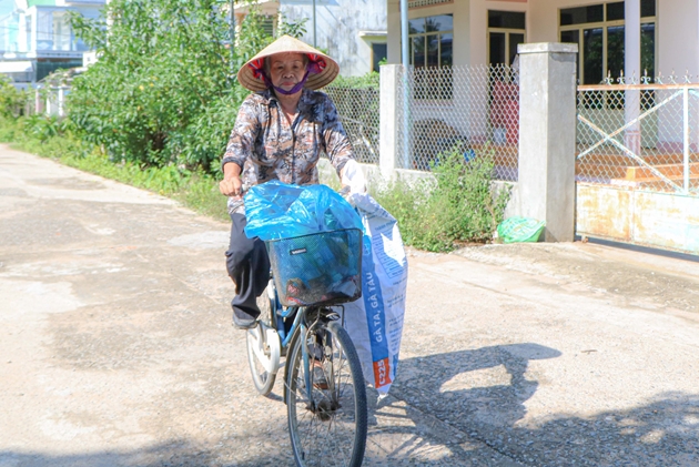 Dù đã 80 tuổi nhưng bà Chích vẫn miệt mài đạp chiếc xe cà tàng rong ruổi khắp các con đường, ngõ hẻm ở thị trấn Tân Sơn để nhặt ve chai giúp đời. Ảnh: Khoa Lê