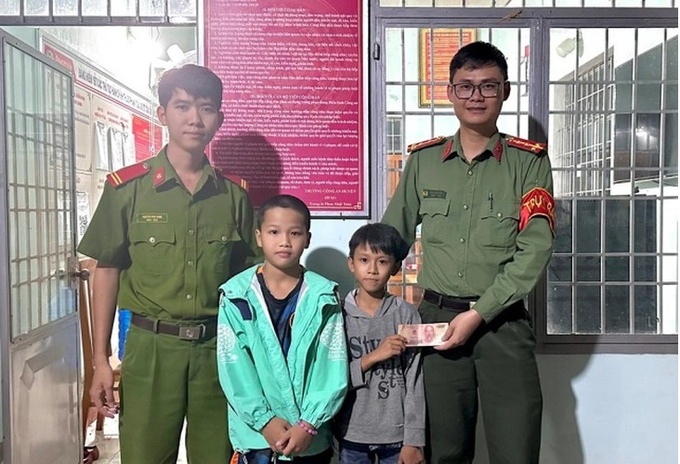 Em Nguyễn Hoàng Anh (9 tuổi) và Nguyễn Sinh Phúc (10 tuổi) nhặt được xấp tiền và tới công an để nhờ tìm người đánh rơi - Ảnh: Công an cung cấp