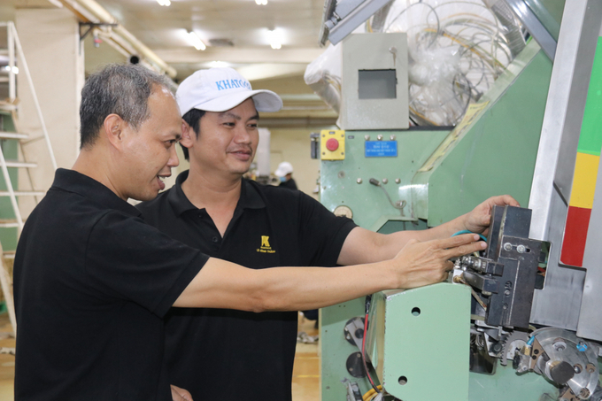 Kỹ sư Nguyễn Duy Khuê (bên trái) cùng đồng nghiệp kiểm tra hoạt động của máy móc tại nhà máy.