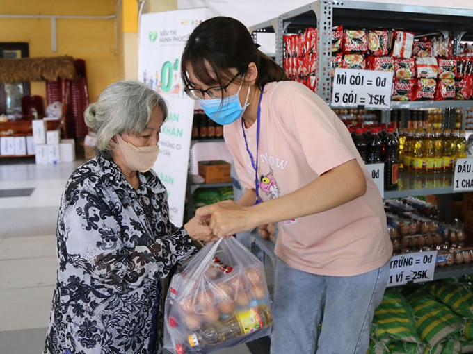 Tình nguyện viên hỗ trợ người dân mua hàng theo phiếu đã đăng ký ở siêu thị 0 đồng bên trong chùa Vĩnh Nghiêm. Ảnh: HOÀNG GIANG