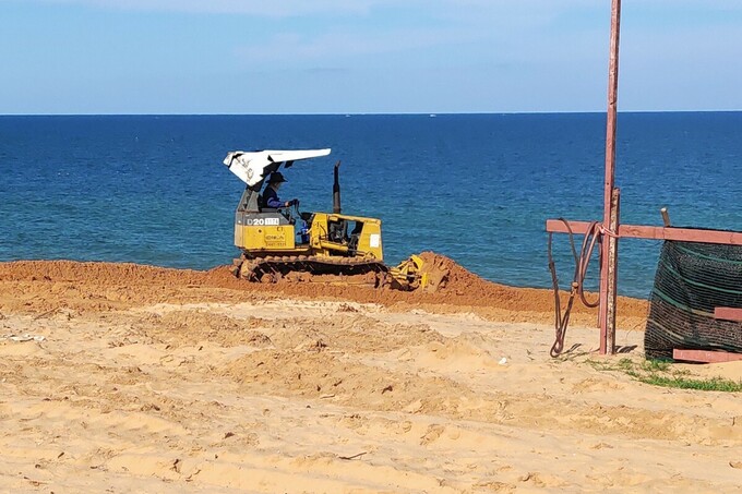 Một tài xế đang điều khiển xe ủi đang san lấp cát ở hiện trường. Ảnh: Việt Quốc.