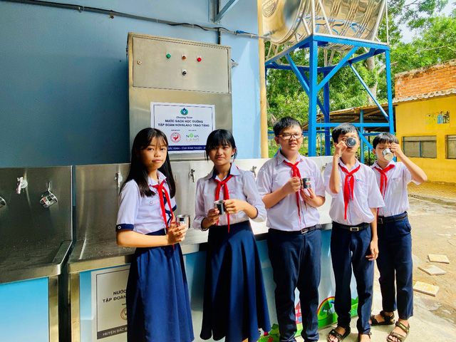 Các em học sinh bên hệ thống máy lọc nước uống sạch vừa được trao tặng