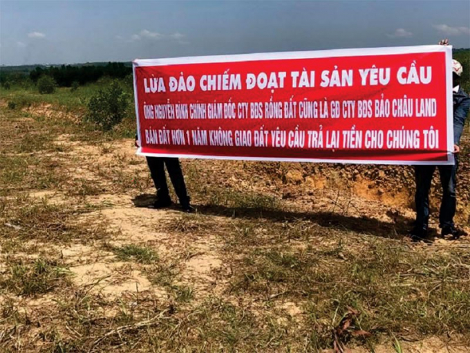 Người dân căng băng rôn tố cáo hành vi lừa đảo và đòi lại tiền đã mua đất của ông Nguyễn Đình Chính. Ảnh: VH