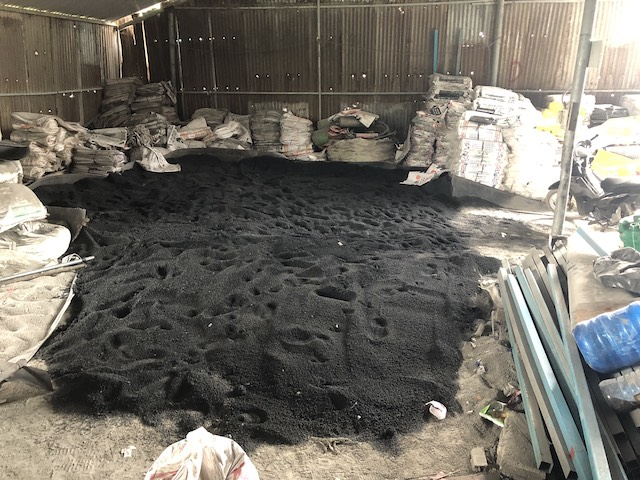 Hàng tấn phân bón màu đen được đổ xuống nền nhà và chưa đóng bao