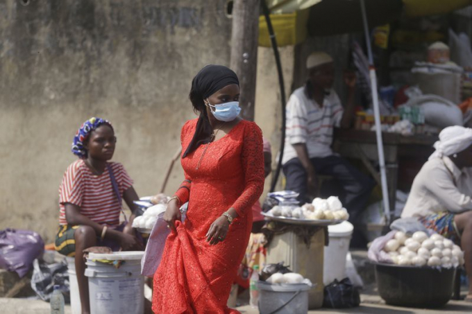 Một phụ nữ đeo khẩu trang đi ngang qua một khu chợ ở Lagos, Nigeria, ngày 24-12. Ảnh: AP