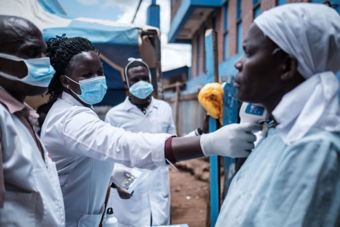 Nhân viên y tế đo nhiệt độ cơ thể của một phụ nữ tại khu ổ chuột Kibera ở Nairobi, vào ngày 18-3. Ảnh: AFP