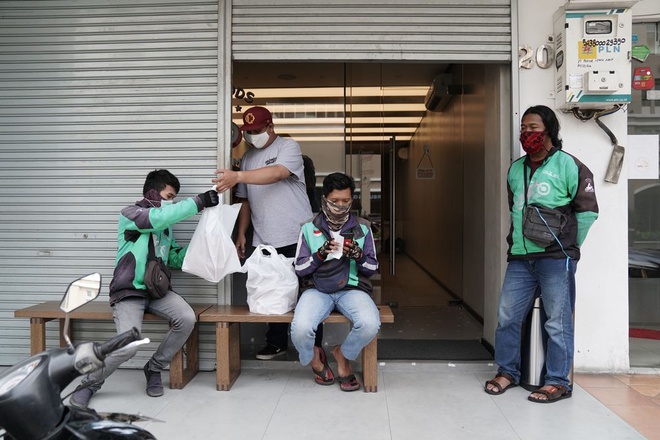 Tài xế Gojek đợi đơn hàng thực phẩm bên ngoài một nhà hàng tại Jakarta, Indonesia. Ảnh: Bloomberg.