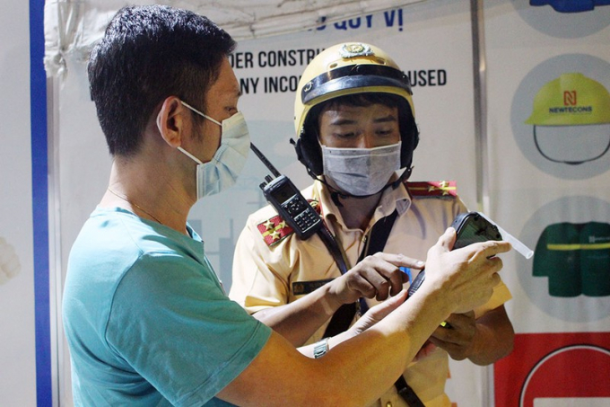 CSGT cho anh Đ. xem tem kiểm định trên máy nhưng anh vẫn không đồng thuận vì cho rằng tem không hiện rõ ngày. Ảnh: LÊ THOA