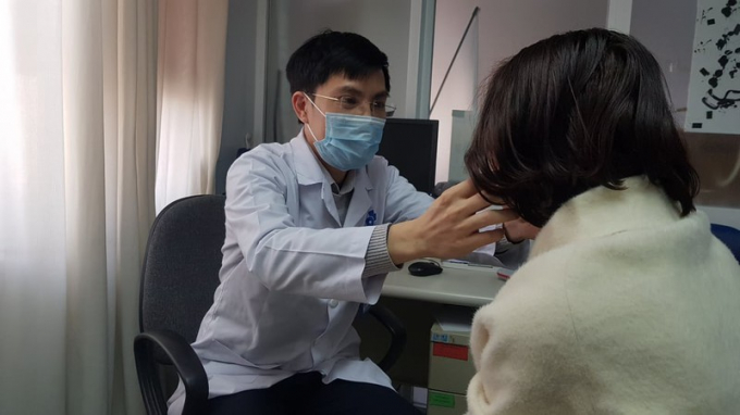 Bác sĩ Quang đang kiểm tra dái tai cho bệnh nhân đến khám. Ảnh: BÁCH AN