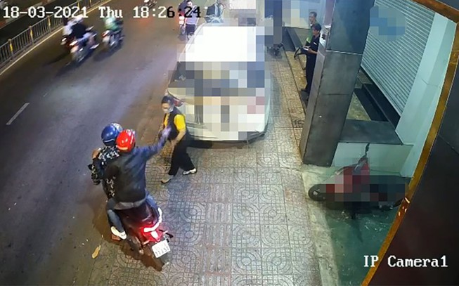 Hai thanh niên bỏ chạy sau khi tạt ca mắm tôm vào người chị T ngay trước trụ sở công ty. Ảnh chụp từ clip