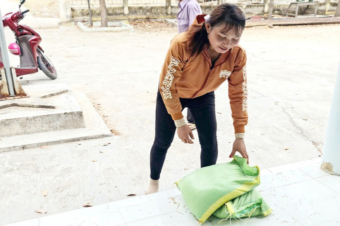 Chị Mang Thị Bé, thôn trưởng thôn Ku Kê, luôn tay luôn chân phân phát gạo cho người dân với nụ cười luôn nở trên môi. Ảnh: P.NAM