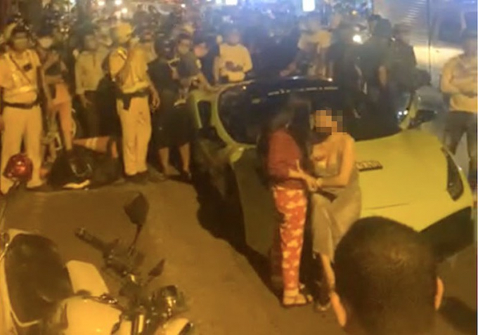 Người phụ nữ mang bầu ngồi trước đầu siêu xe. Ảnh cắt từ clip