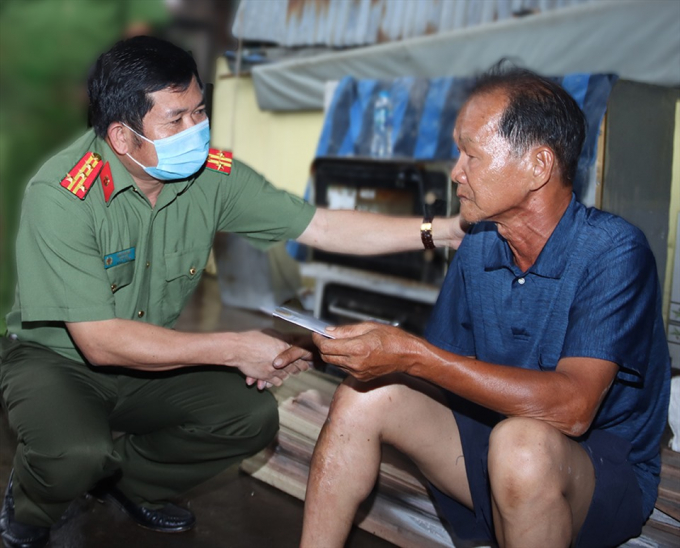 Đại tá Đinh Văn Nơi thăm hỏi và hỗ trợ hộ dân bị hỏa hoạn tại phường Mỹ Long vào ngày 21.5.2021. Ảnh: CAAG