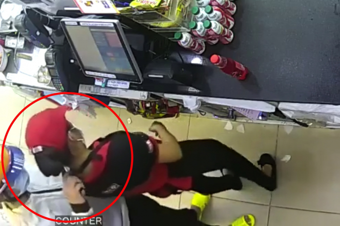 Tên cướp kề dao vào cổ để uy hiếp nữ nhân viên (Ảnh cắt từ clip).
