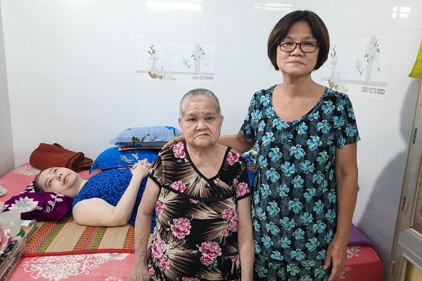 Bà Từ Thị Nga (đứng) hằng ngày đi làm mướn để chăm sóc chị gái già lẩn thẩn và cháu gái nằm liệt giường.