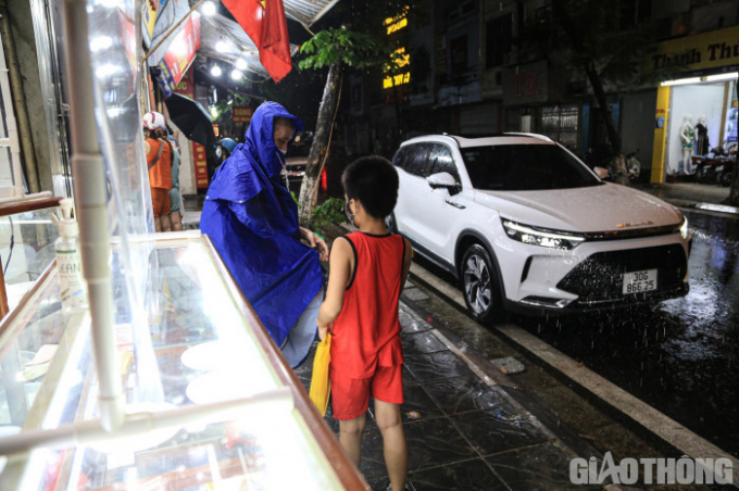 Đến gần 20h, Hà Nội đổ mưa lớn. Một số người vẫn cố nán lại ở cửa hàng để mua những hộp bánh trung thu truyền thống.