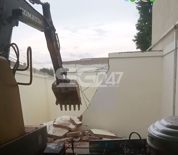 Xe múc đang dở bức tường bên trong quán của ông Lợi.