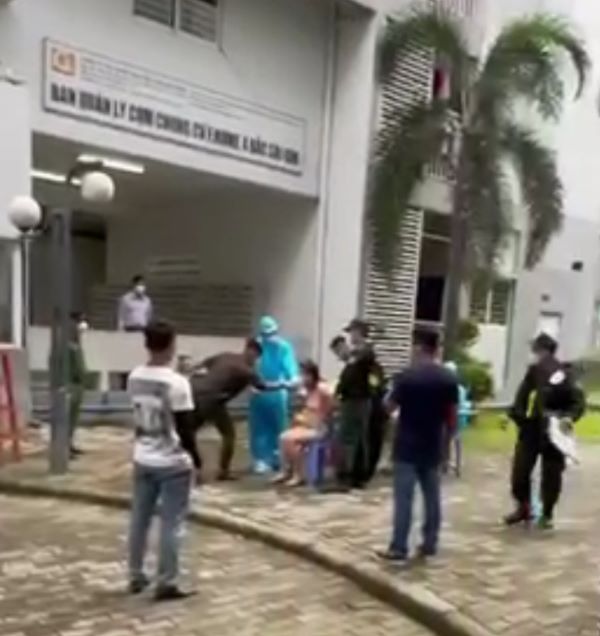 Bà P.L bị giữ hai tay và ngồi trên ghế trước sự chứng kiến của nhiều người