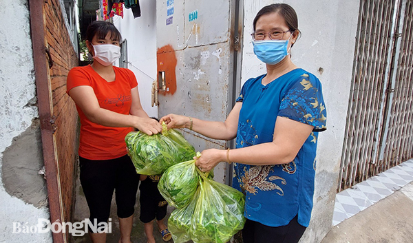 Bà Bùi Thị Liên Phương (phải) tặng quà cho người dân ở tổ 48, KP.11, P.Tân Phong gặp khó khăn do đại dịch Covid-19