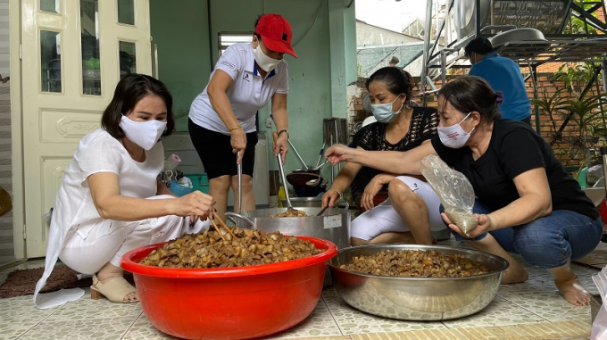 Bà Nguyễn Thị Bông - Chủ nhiệm CLB Sen Hồng (bìa trái) cùng bà Trần Thị Bông - thành viên CLB - Chủ Bếp cơm Nhà Bông, TX Phước Long (thứ 2, trái sang) đang làm món thịt kho để gửi tặng người dân về quê tránh dịch