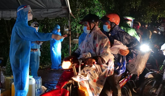 Anh Trần Văn Vũ - con trai bà Nguyễn Thị Bông - Chủ nhiệm CLB Sen Hồng (bìa trái) trao tiền hỗ trợ xăng xe cho dòng người ồ ạt về quê tránh dịch, đi qua chốt phòng chống dịch số 2 (H.Đồng Phú)